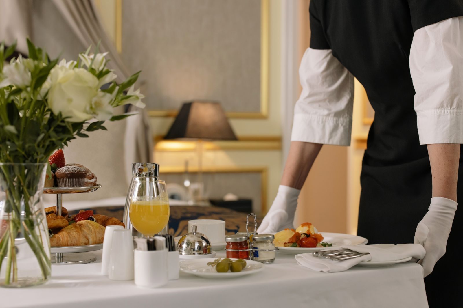 Staff member in white gloves serving an in-room breakfast